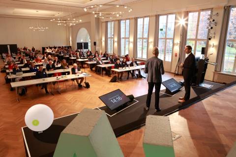 Blick von der B&uuml;hne auf Moderator und Gast im Gespr&auml;ch sowie im Hintergrund die Teilnehmenden des Kongresses.