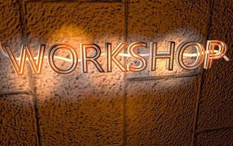 Vor einer braunen Wand mit strukturierter Oberfl&auml;che ist der beleuchtete Schriftzug "Workshop" zu sehen.